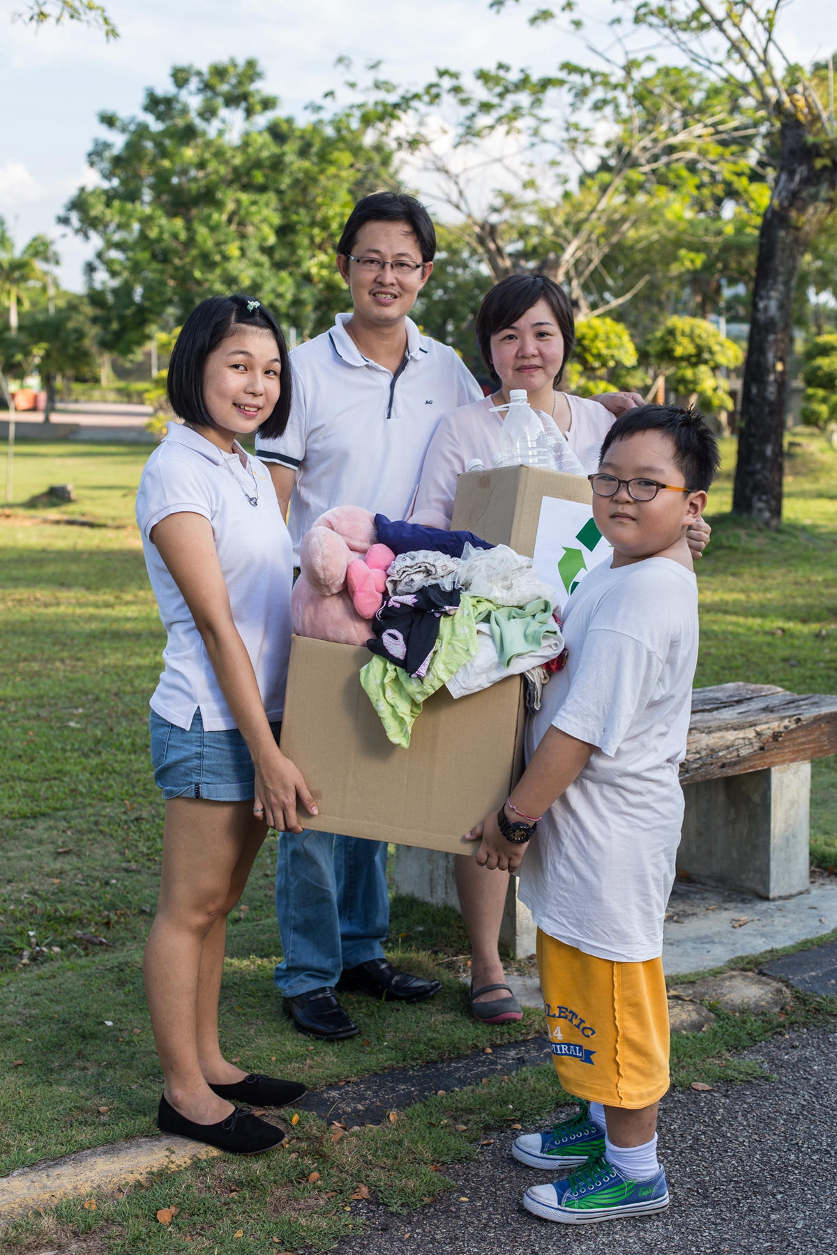 Family donating old clothes to Yellow Bin textile recycling bin in Johor Bahru